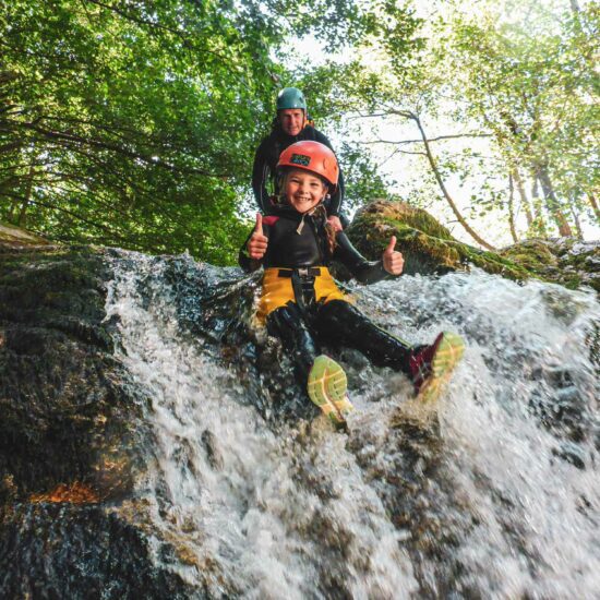 Enfant glissant sur un toboggan dans le canyon famille du parcours canyoning de l'Azéro avec Nature Canyon Ardèche