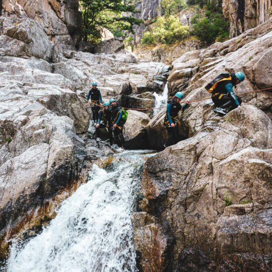 Groupe d'amis traversant la rivière du Chassezac encordés à une corde lors d'une sortie canyoning découverte avec Nature Canyon Ardèche