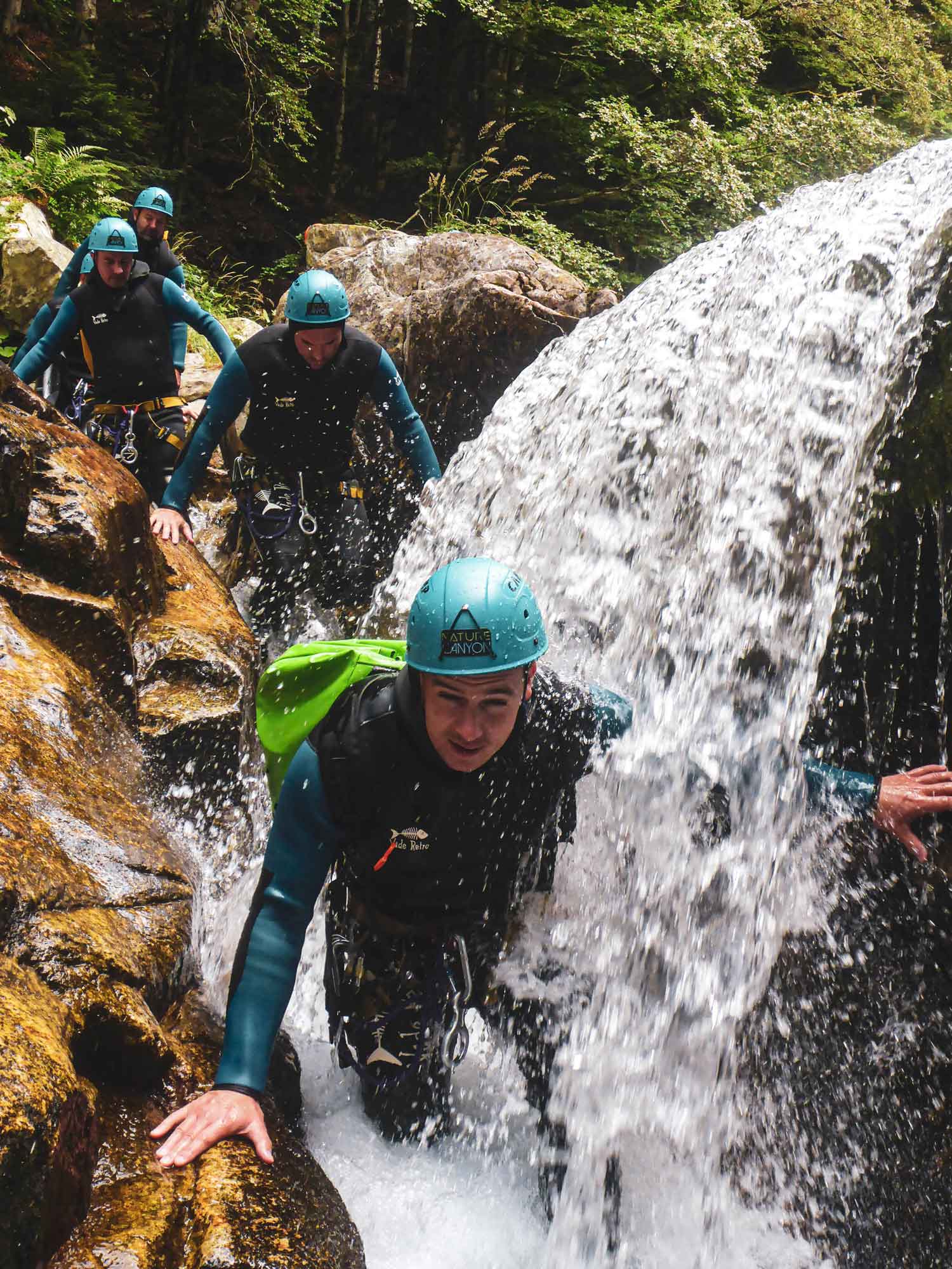 Groupe de personnes marchant dans un bief avec une chute d'eau sur le parcours canyoning de la Borne avec Nature Canyon Ardèche