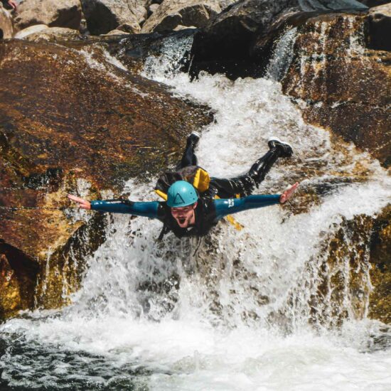 Un pratiquant glissant sur le ventre la tête en avant sur un toboggan naturel sur le parcours canyoning du Chassezac en Lozère avec Nature Canyon Ardèche