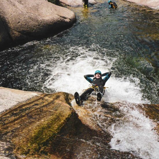 Jeune homme glissant sur un toboggan naturel sur le parcours canyoning du Chassezac en Lozère avec Nature Canyon Ardèche